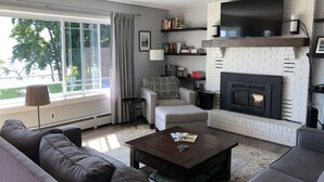 Uma sala de estar moderna com lareira, sofá, mesa de centro e televisão na parede.