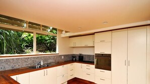 A modern kitchen with white cabinets, a wooden countertop, and a built-in oven.