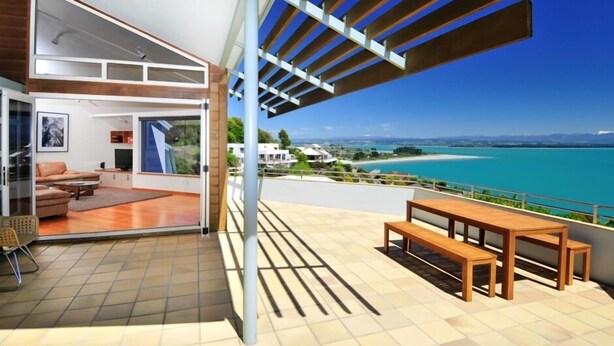 A modern interior with a balcony overlooking a scenic coastal view.