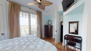 Ein Schlafzimmer mit einem Bett, einem Schreibtisch, einem Stuhl, einer Kommode und einem Deckenventilator.