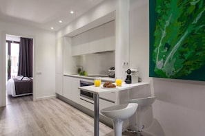 A modern kitchen with a breakfast bar, a coffee machine, and a fruit bowl.