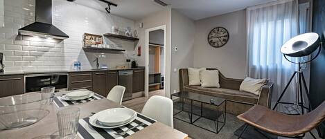 A modern kitchen with white subway tiles, a black range hood, and a dining area with a table set for two.