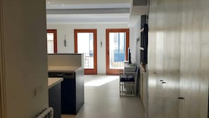 Cozinha moderna com lava-louças, um pequeno espaço de jantar com uma cadeira e vista para o exterior através de uma porta.