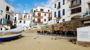 Uma rua estreita com edifícios em ambos os lados, um barco coberto por uma lona e mesas ao ar livre.