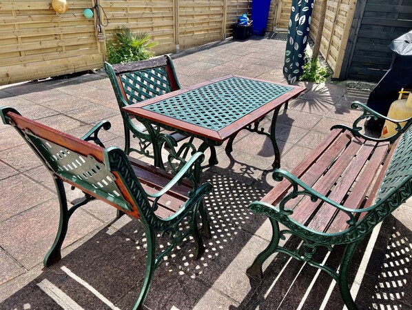 A patio area with a wooden table and four green metal chairs. - Waterside Cottage Wadebridge River views Camel Trail Cycling Free Wi-Fi Cornwall (Wadebridge)