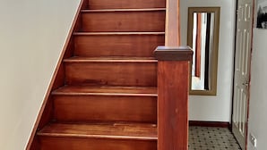 A wooden staircase with a handrail, leading to a room with a tiled floor and a door with a window. - Waterside Cottage Wadebridge River views Camel Trail Cycling Free Wi-Fi Cornwall (Wadebridge)