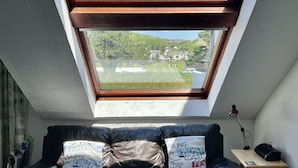 A room with a skylight, a black leather sofa, and a small table with a lamp. - Waterside Cottage Wadebridge River views Camel Trail Cycling Free Wi-Fi Cornwall (Wadebridge)