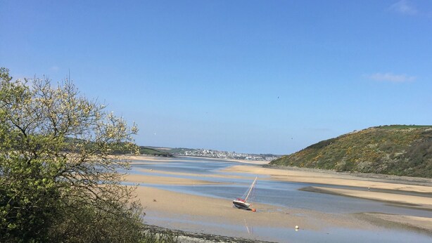 A coastal landscape with a sandy beach, a small boat, and a hill with sparse vegetation. - Waterside Cottage Wadebridge River views Camel Trail Cycling Free Wi-Fi Cornwall (Wadebridge)