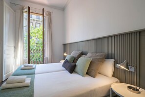 A hotel room with two beds, a view of greenery outside, and a modern headboard. - Barcelona Balconies 10 - Habitat Apartments (Barcelona)