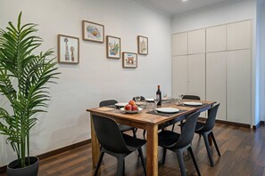 A dining area with a wooden table, black chairs, a potted plant, and framed artwork on the wall. - Barcelona Balconies 10 - Habitat Apartments (Barcelona)
