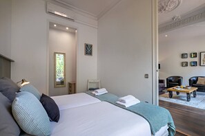 A hotel room with a large bed, a sitting area with a coffee table, and a view through a glass door. - Barcelona Balconies 10 - Habitat Apartments (Barcelona)