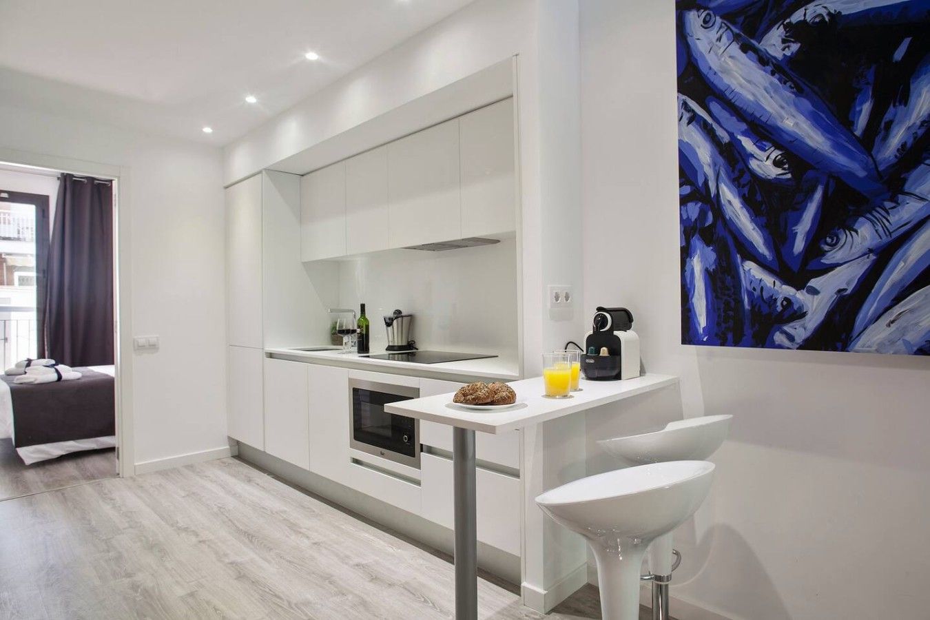 A modern kitchen with white cabinetry, a built-in oven, and a coffee machine.