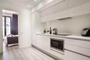 A modern kitchen with white cabinetry, a built-in oven, and a toaster.