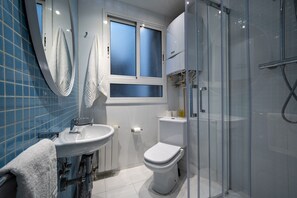 A modern bathroom with a glass shower enclosure, a white sink, and a toilet.