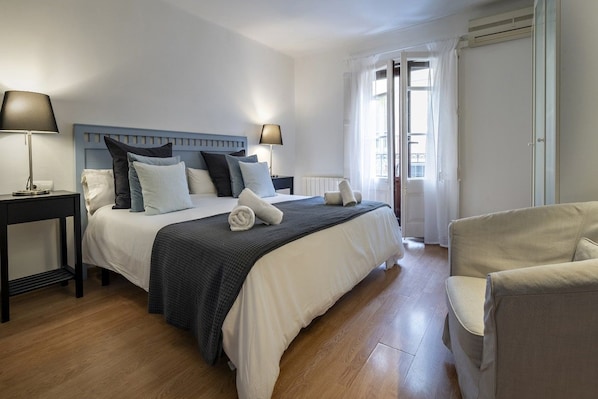 A hotel room with a bed, two bedside tables, a chair, and a window with curtains.