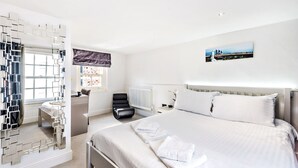 A modern hotel room with a large bed, a desk, a chair, and a mirror. - Modern, Chic 3BR Townhouse in Central Oxford - Pass the Keys (Oxford)