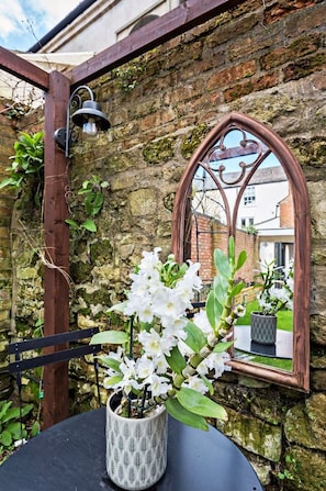 A rustic outdoor seating area with a metal table and a potted plant.