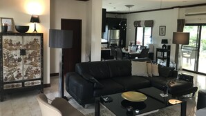 Una sala de estar moderna con un sofá de cuero negro, una mesa de centro de vidrio y un comedor con un gran ventanal.