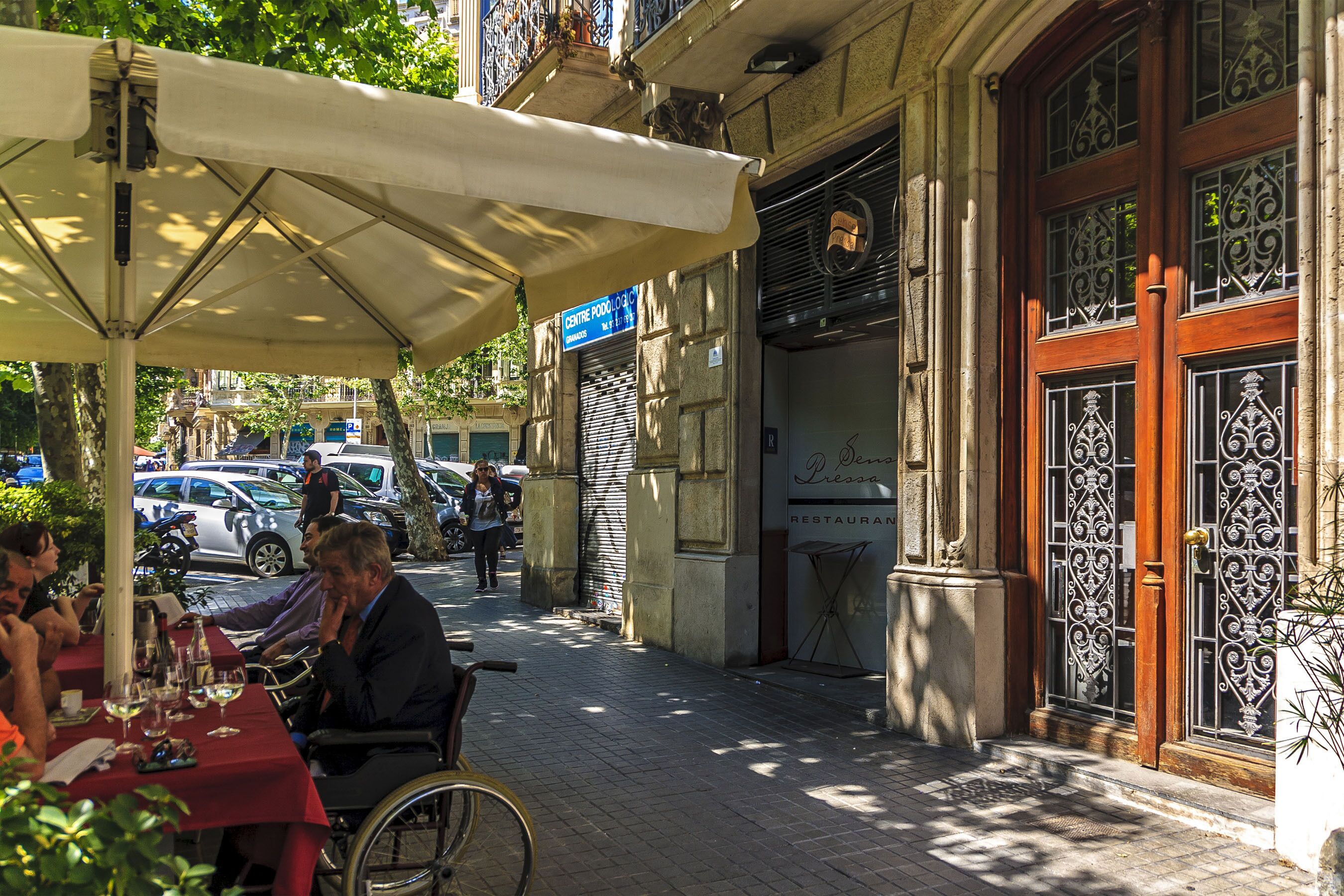 A street scene with a café, outdoor seating, and a building with a closed shutter.