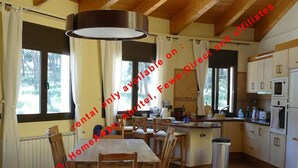 A dining area with a table and chairs, a kitchen with appliances, and a view of the outdoors. - Superb Villa 8-10 persons with private pool, near beach (Pals)