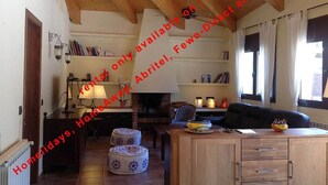 A cozy living room with a fireplace, wooden beams, a sofa, a dining table, and a bookshelf. - Superb Villa 8-10 persons with private pool, near beach (Pals)