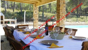 An outdoor dining area with stone pillars, wooden tables, and chairs. - Superb Villa 8-10 persons with private pool, near beach (Pals)