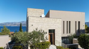 A modern building with a stone facade, a flat roof, and a large window.