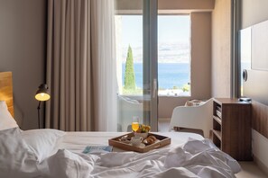 A hotel room with a bed, a bedside table with a tray of breakfast, a lamp, and a view of the sea. - Villa Ana — Private Sea Ray 230 SPX OB Yacht & Mercedes V-Class with Driver (Splitska)