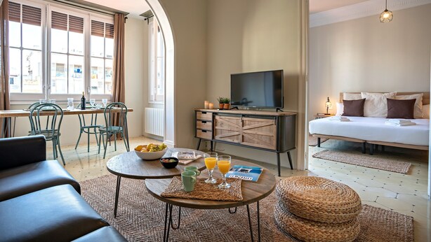 A modern living room with a sofa, coffee table, and breakfast setup. - Bailén Style - Habitat Apartments (Barcelona)