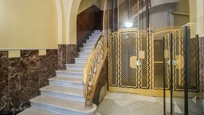 A marble staircase with ornate golden railings and a decorative gate at the top. - Bailén Style - Habitat Apartments (Barcelona)