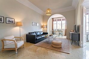 A living room with a sofa, armchair, coffee table, and a television.