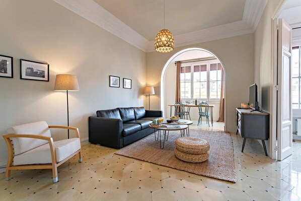 A living room with a sofa, armchair, coffee table, and a television.