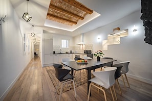 A modern kitchen with a central island, white cabinetry, and a dining area with a wooden table and chairs.