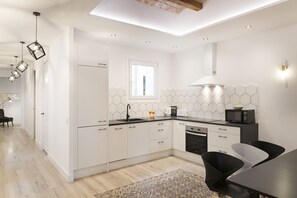 Une cuisine moderne avec des meubles blancs, un plan de travail noir et un four encastré.