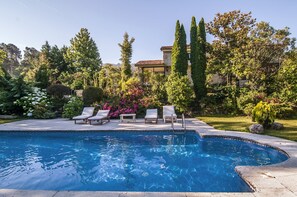 A swimming pool with lounge chairs and a well-maintained garden.