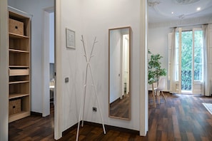 A hallway with a wooden floor, a white door with a mirror, and a view of a dining area with a plant. - Barcelona Balconies 11 - Habitat Apartments (Barcelona)