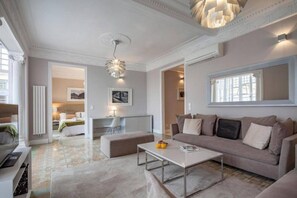 A modern living room with a sofa, coffee table, and a dining area with a chair and table.