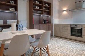 A modern kitchen with a dining area, featuring a white table, chairs, and a patterned rug.