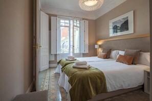 A hotel room with two beds, a large window, and a painting on the wall. - Huge Eixample Luxury Flat Barcelona Classic (Barcelona)