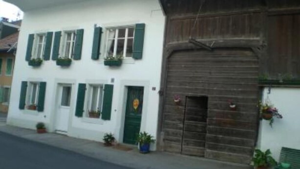 Ein weißes Gebäude mit grünen Fensterläden und einer Holztür.