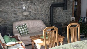 Ein gemütliches Wohnzimmer mit Steinwand, einer Couch, einem Holztisch und einem Sessel.