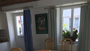 Ein Essbereich mit einem Tisch, der mit einer gemusterten Tischdecke bedeckt ist, umgeben von Holzsesseln mit gepolsterten Sitzen.