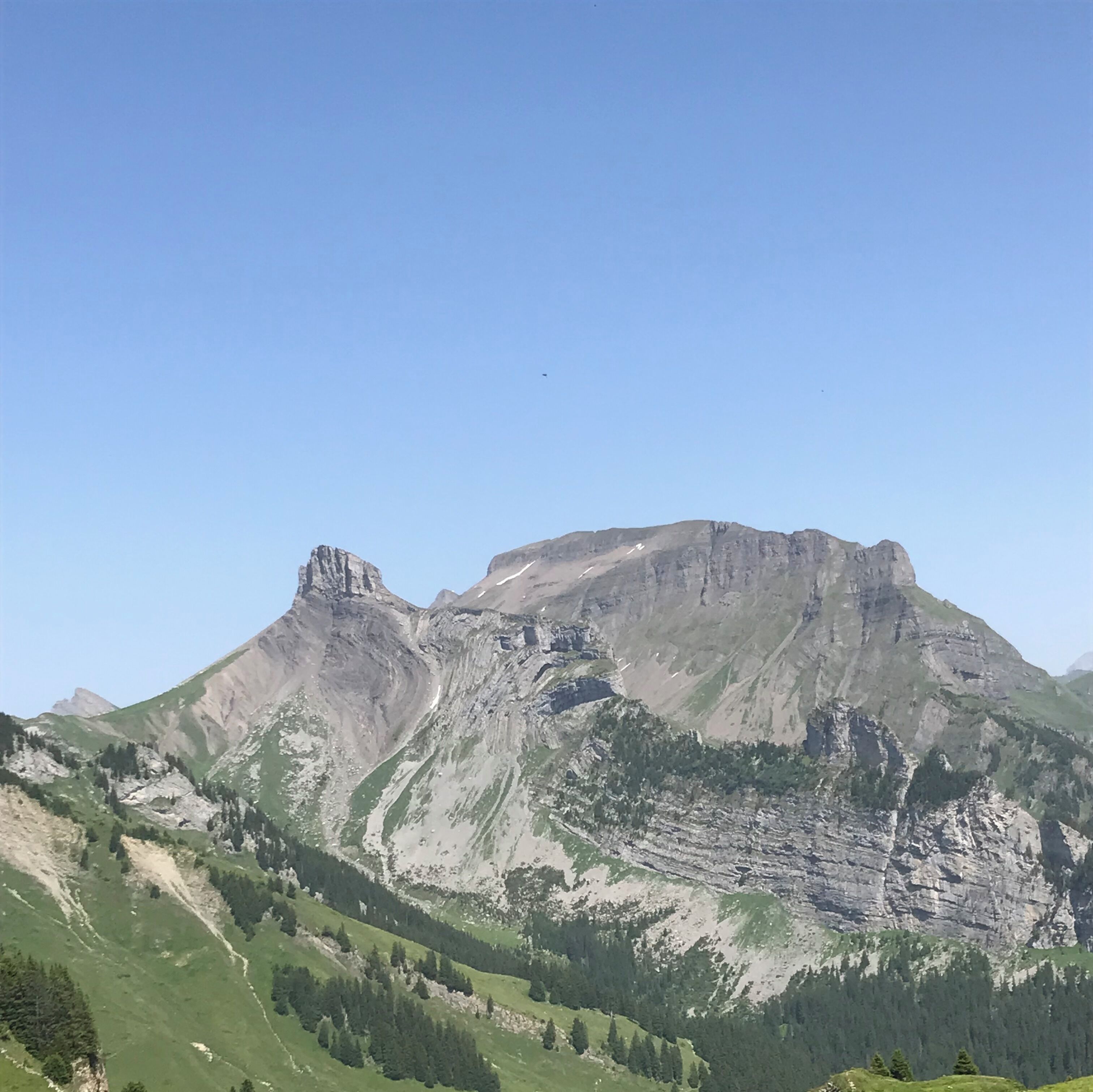 A mountain with a prominent peak and a valley with green vegetation.