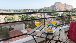 A balcony with a table set for two, overlooking a cityscape. - Cascais Panoramic with Pool by Portugal Portfolio (Cascais)