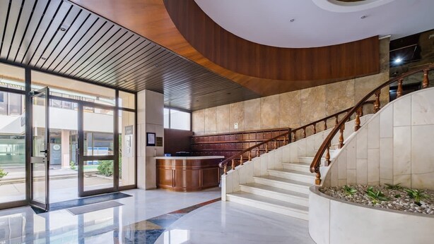 A modern lobby with a curved staircase, a reception desk, and a glass entrance. - Cascais Panoramic with Pool by Portugal Portfolio (Cascais)