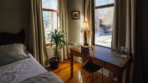 A hotel room with a bed, a desk with a chair, a potted plant, a lamp, and a view of the outside. - Montreal Plateau Mont Royal: apartments - 5 rooms - 4/6 persons (Montréal (Plateau Mont-Royal))