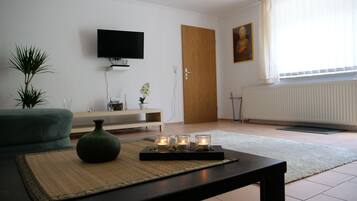 Ein Wohnzimmer mit Flachbildfernseher, Holztür, Gemälde und Pflanze.