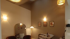 Une pièce chaleureuse avec une table ronde, deux chaises, une lampe et des appliques murales.