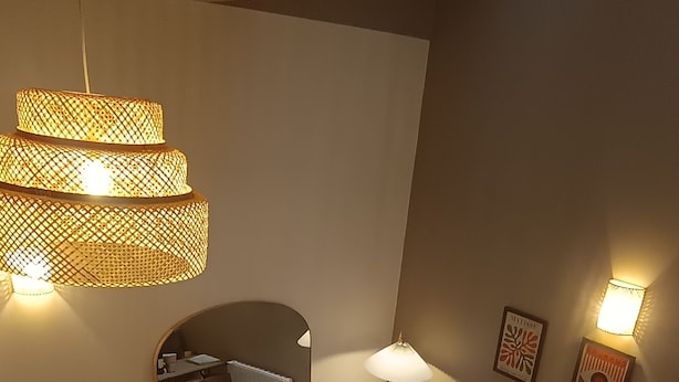 Un salon moderne avec une table basse ronde, deux fauteuils, une table à manger avec des chaises et une grande fenêtre.
