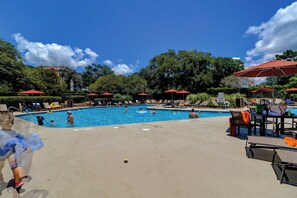 A pool area with multiple swimming pools, lounge chairs, and umbrellas.